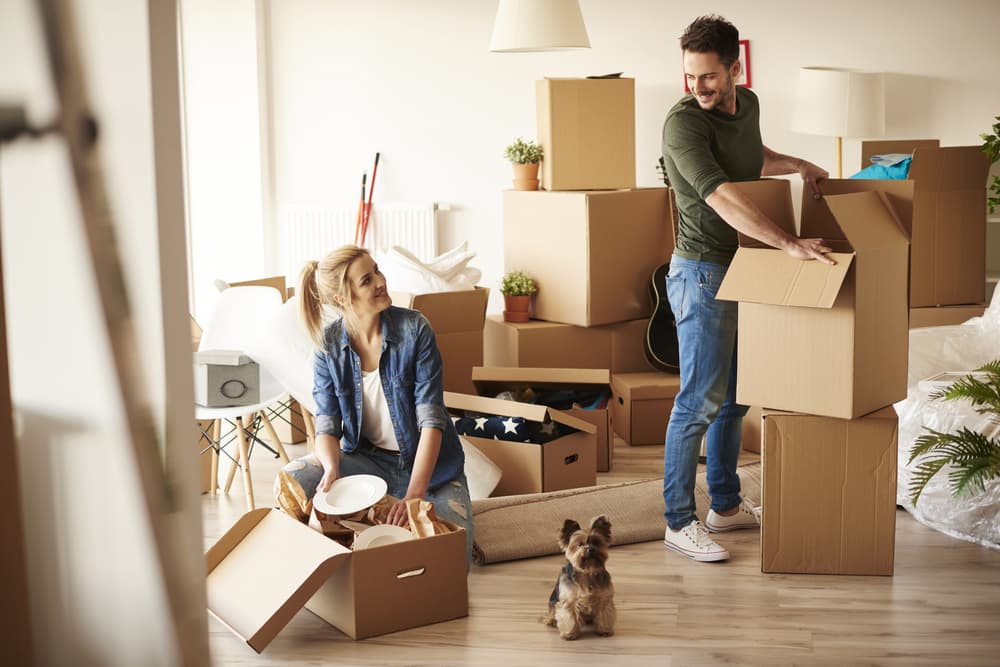 A man and woman prepare for a big move as they unpack boxes in their new home.