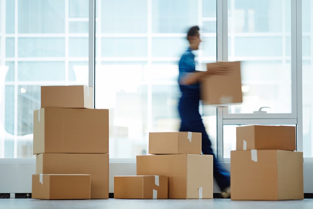 A man carrying boxes in front of an office window.