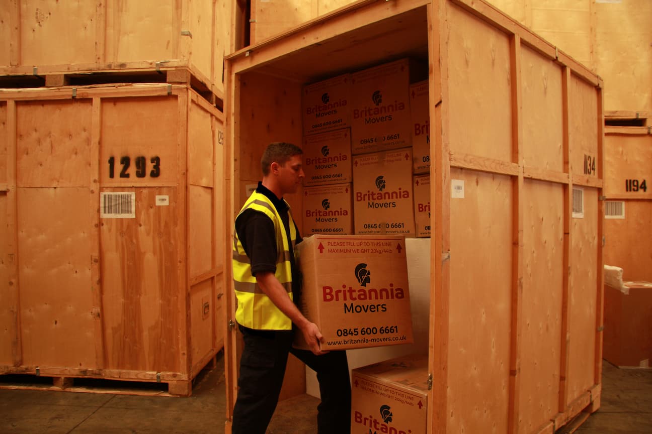 A man loading boxes into a wooden crate for household storage